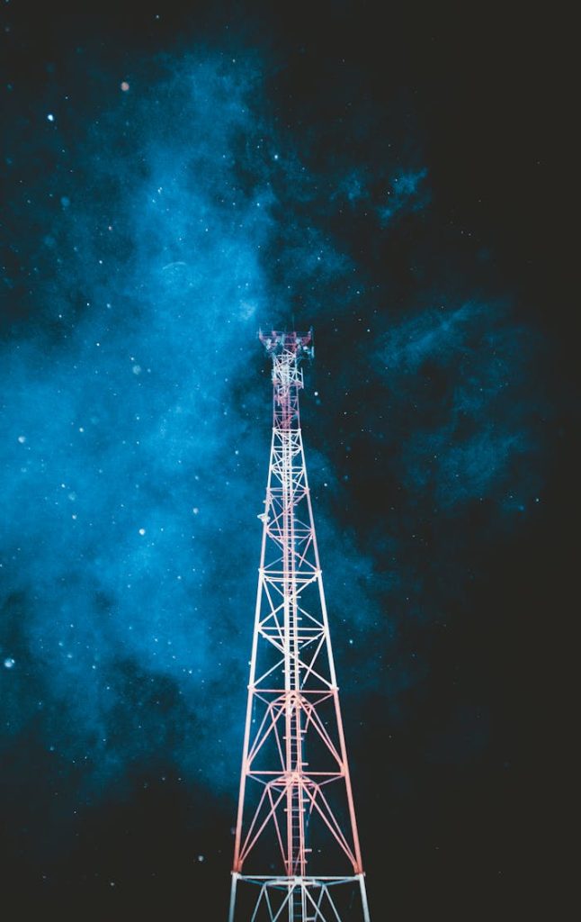 A striking telecommunication tower stands beneath a vibrant starry night sky.